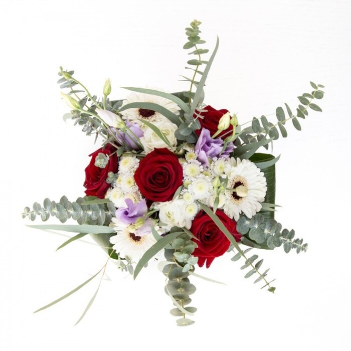 From the perspective of a Blackheath florist, this bouquet embodies a subtle sophistication, each element precisely chosen to evoke connection and warmth. Deep red roses stand at the center, their spiral petals unfurling with a sense of enduring love and trust, while white gerbera daisies with coffee-hued eyes radiate brightness, reminiscent of the crisp light at Blackheath station in the early hours. A scattering of lilac lisianthus adds a gentle, contemporary accent; their airy blooms and partially closed buds conjure the quiet promise of a spring morning along Greenwich Park's edge. Circles of eucalyptus, cool and silvery, arch above the bouquet, carrying a clean, invigorating scent, much like the refreshing breeze flowing across Blackheath Common. Fluffy clusters of ivory filler blossoms settle between the larger flowers, their softness creating depth and a sense of generosity. Shiny, broad leaves wrap protectively about the base, drawing the arrangement together with sturdy grace. Whether presented to mark a personal milestone, offer sympathy, or simply bring a touch of beauty to a Blackheath home, this bouquet is crafted as a reflection of local artistry and the serene, open spirit of SE3.