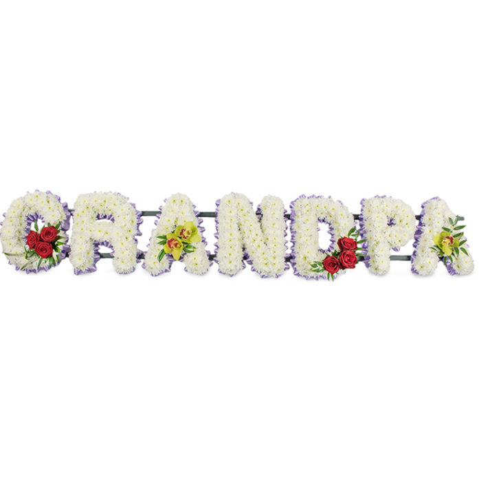 In this detailed sympathy display, the word GRANDPA is presented in large, flower-covered letters aligned horizontally, standing out vividly against a plain white background that emphasises both structure and colour. Every letter is composed of numerous small, crisp white chrysanthemums, each bloom carefully angled so the petals form a dense, textured surface that feels full and comforting, reminiscent of a soft blanket laid out for a quiet moment on Blackheath's green expanses. Encircling the edge of each letter is a slender border of soft lavender or lilac ribbon, providing just enough contrast to define the shapes while preserving the gentle, understated palette. Within this field of white, selective accent flowers add stories of love and personality. The graceful curve of the initial G holds a compact cluster of three or four deep red roses, their rich hue and velvety petals suggesting enduring love, surrounded by polished, deep green leaves. The first decorated A in the sequence is embellished with yellow-green orchids, their elongated petals and lightly speckled throats lending an air of refinement and uniqueness. Mirroring the opening curve, the rounded D encloses another cluster of red roses, reinforcing the tribute's emotional heartbeat. The final A echoes the first orchid accent, balancing the design so that colour flows gently from one side of the word to the other. Subtle metal or wooden bars serve as a framework behind the flowers, keeping each letter level and unified, ready to be placed at the front of a chapel, crematorium, or graveside around Blackheath. Crafted with evident care and precision by experienced florists, this funeral arrangement radiates peace, dignity, and heartfelt gratitude for a much-loved grandfather, turning a single word into a tender floral memory.
